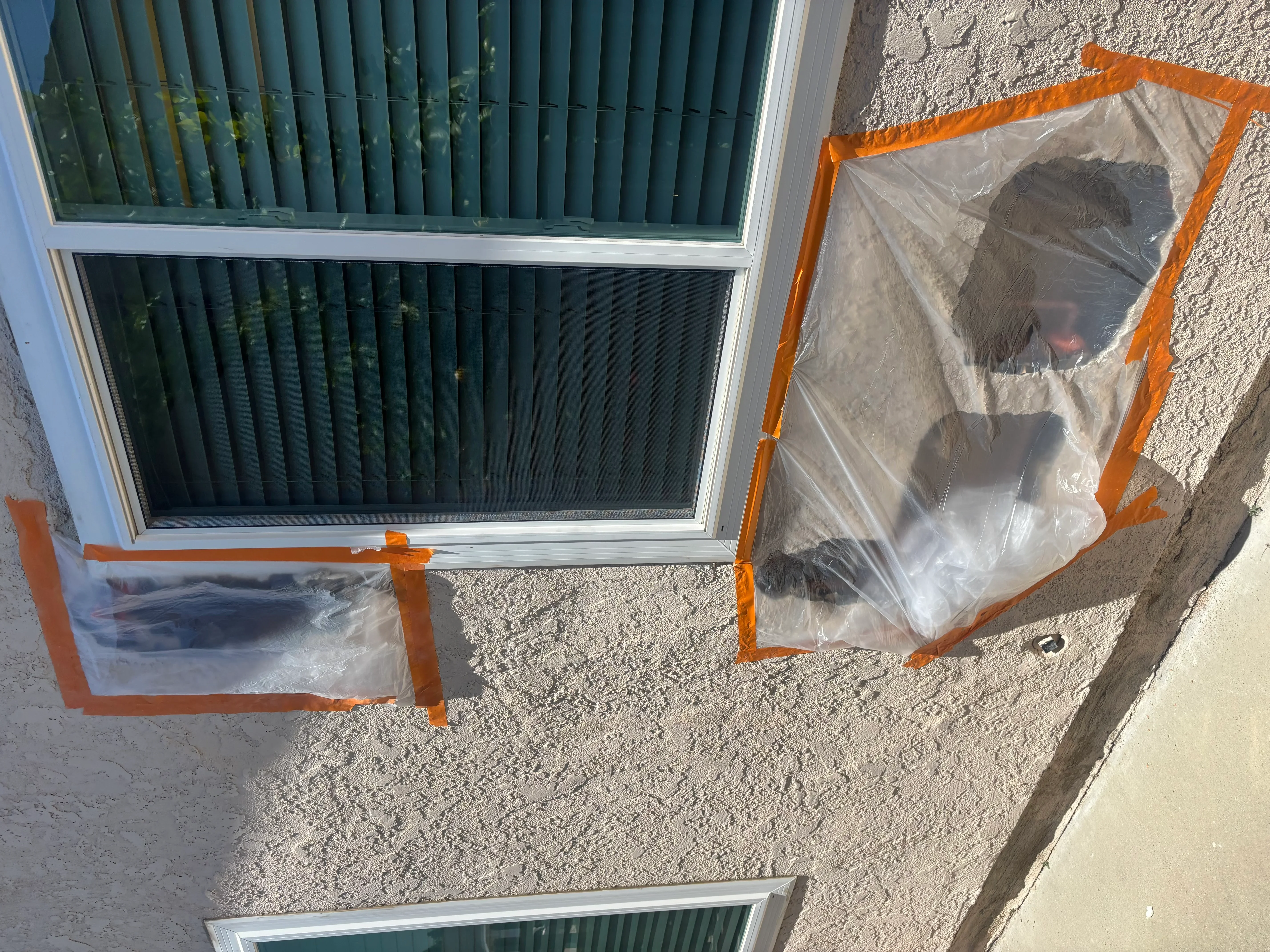 Exterior windows protected with plastic sheeting and orange reinforced frames during plumbing service