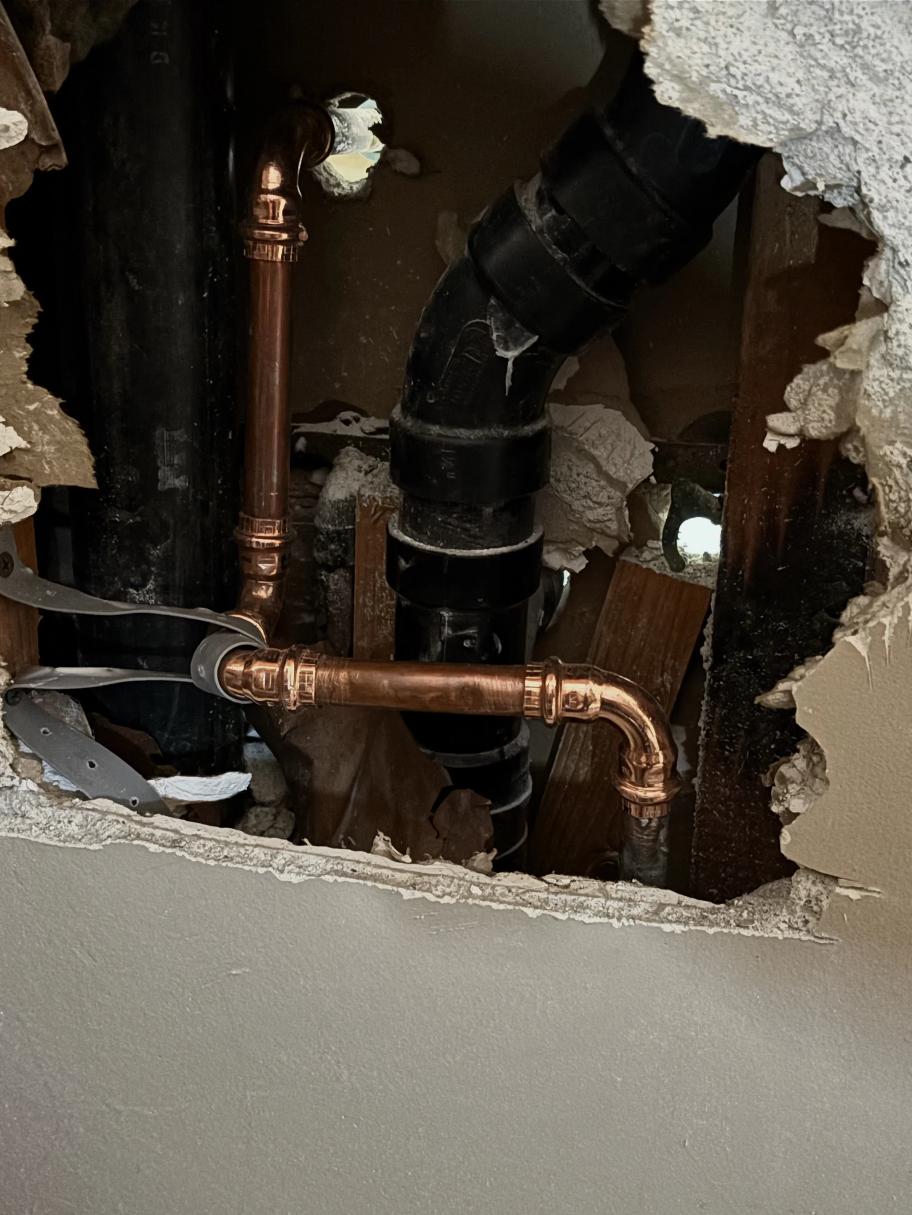 Copper drain pipe with brass fittings installed in basement framing