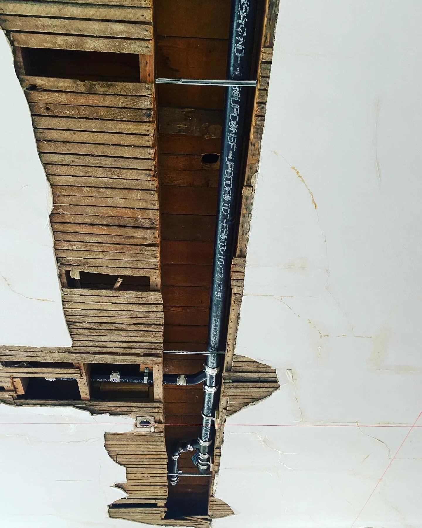 PVC drain lines, vent stack, and metal couplings installed in residential framing
