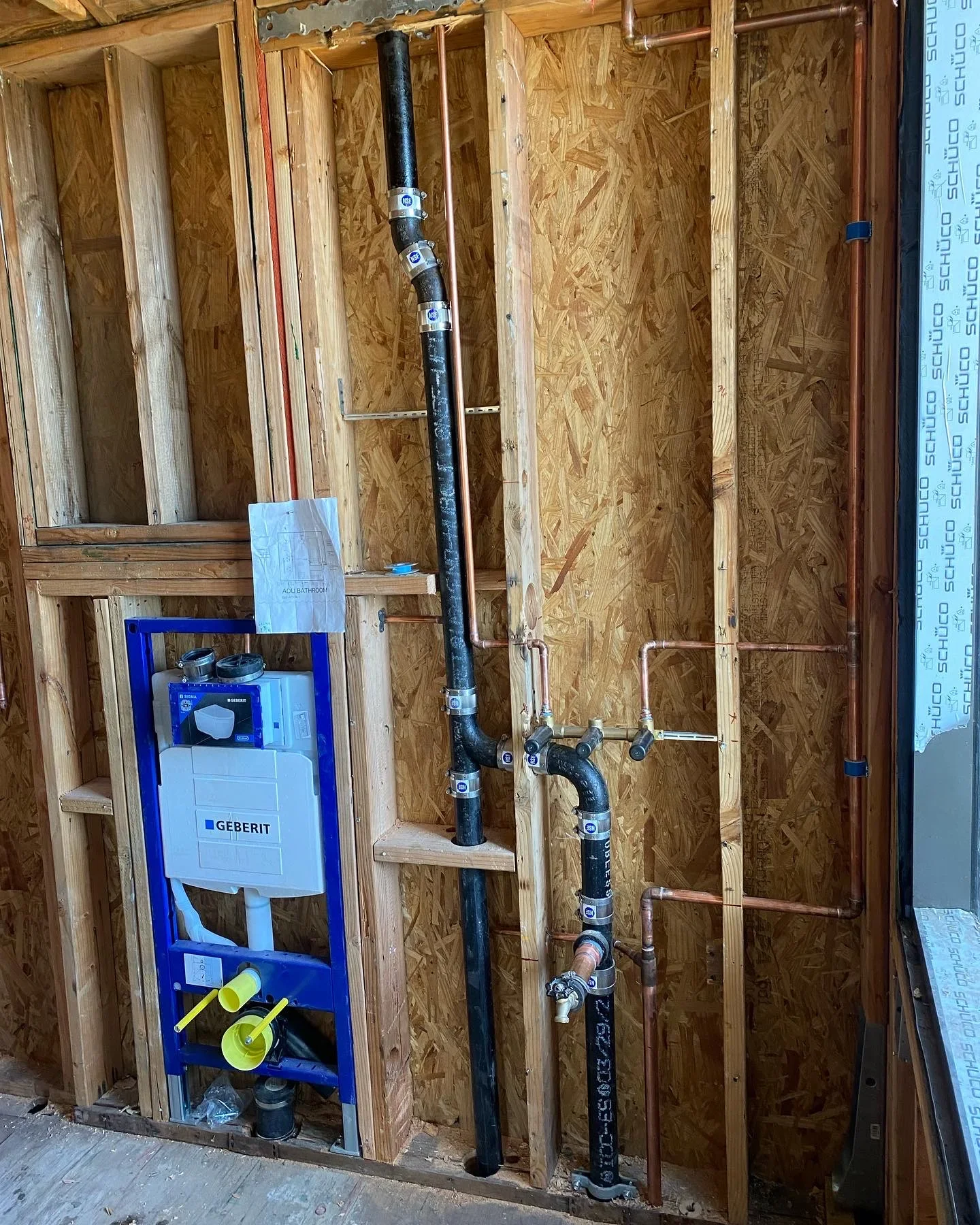 Geberit in-wall toilet tank with black PEX and copper supply lines installed in framed wall cavity