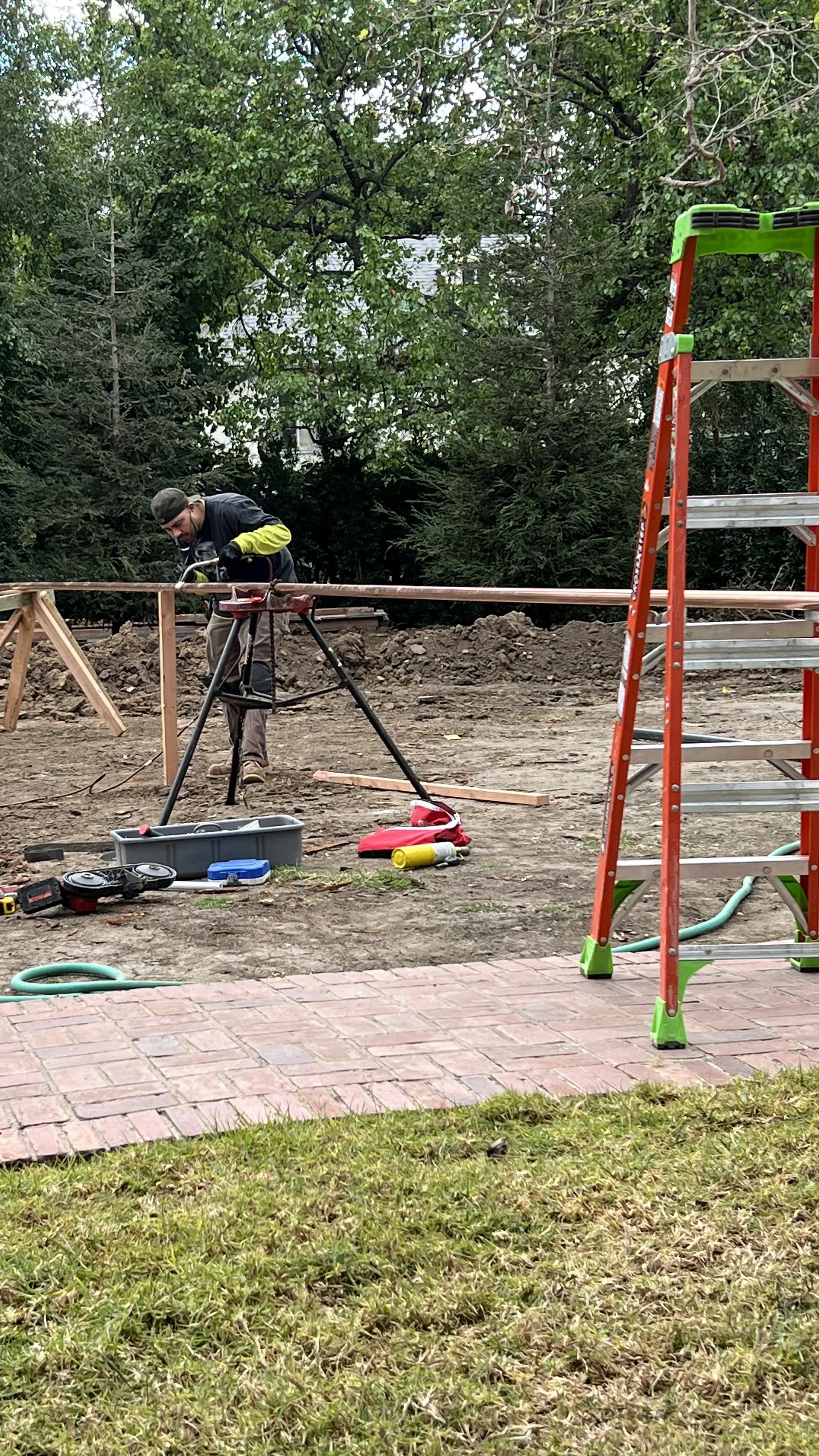 Plumber cutting and fitting metal pipe with professional tools on residential job site