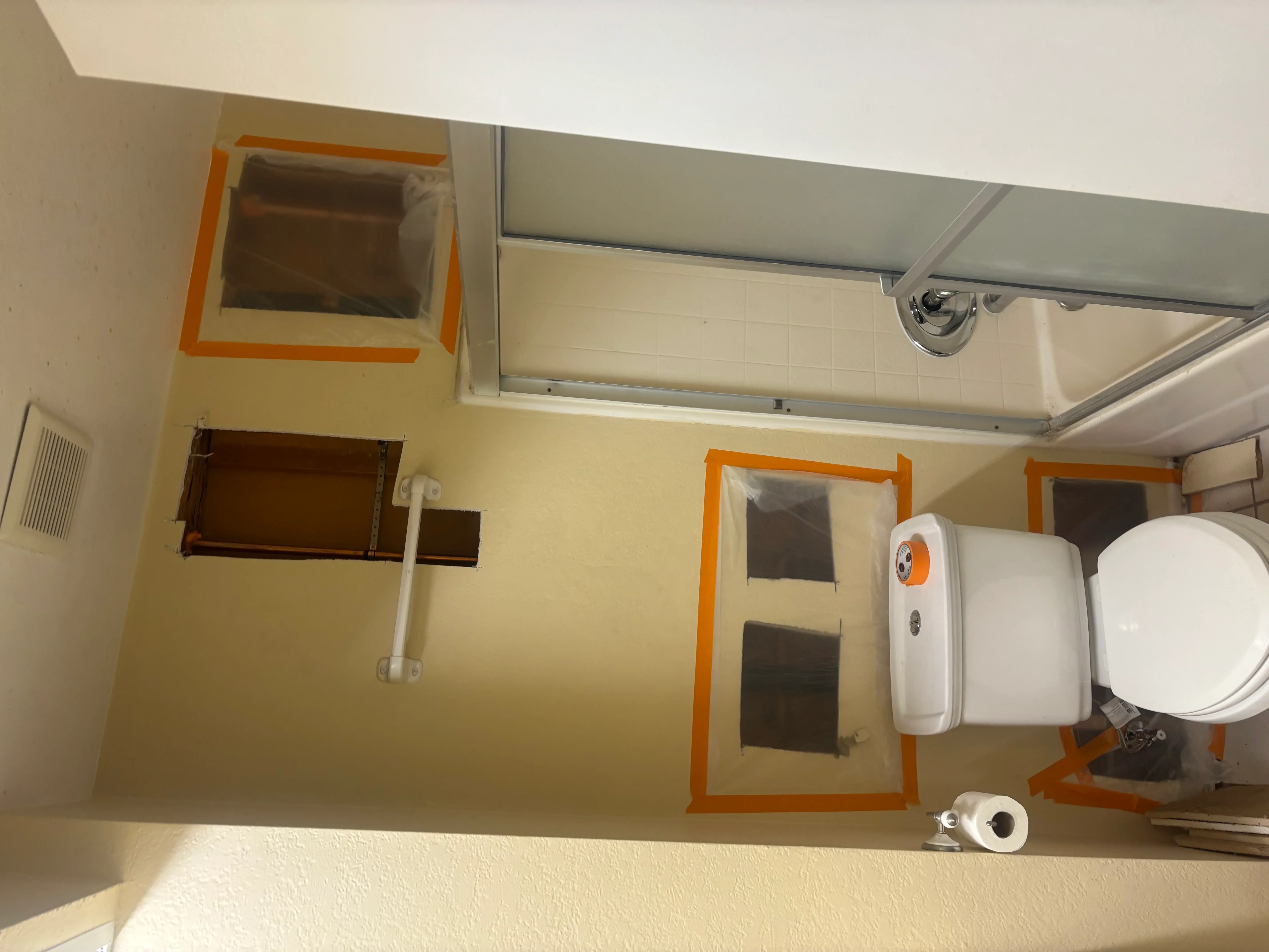 Bathroom rough-in plumbing with PVC pipes, orange fixture frames, and drain line installations