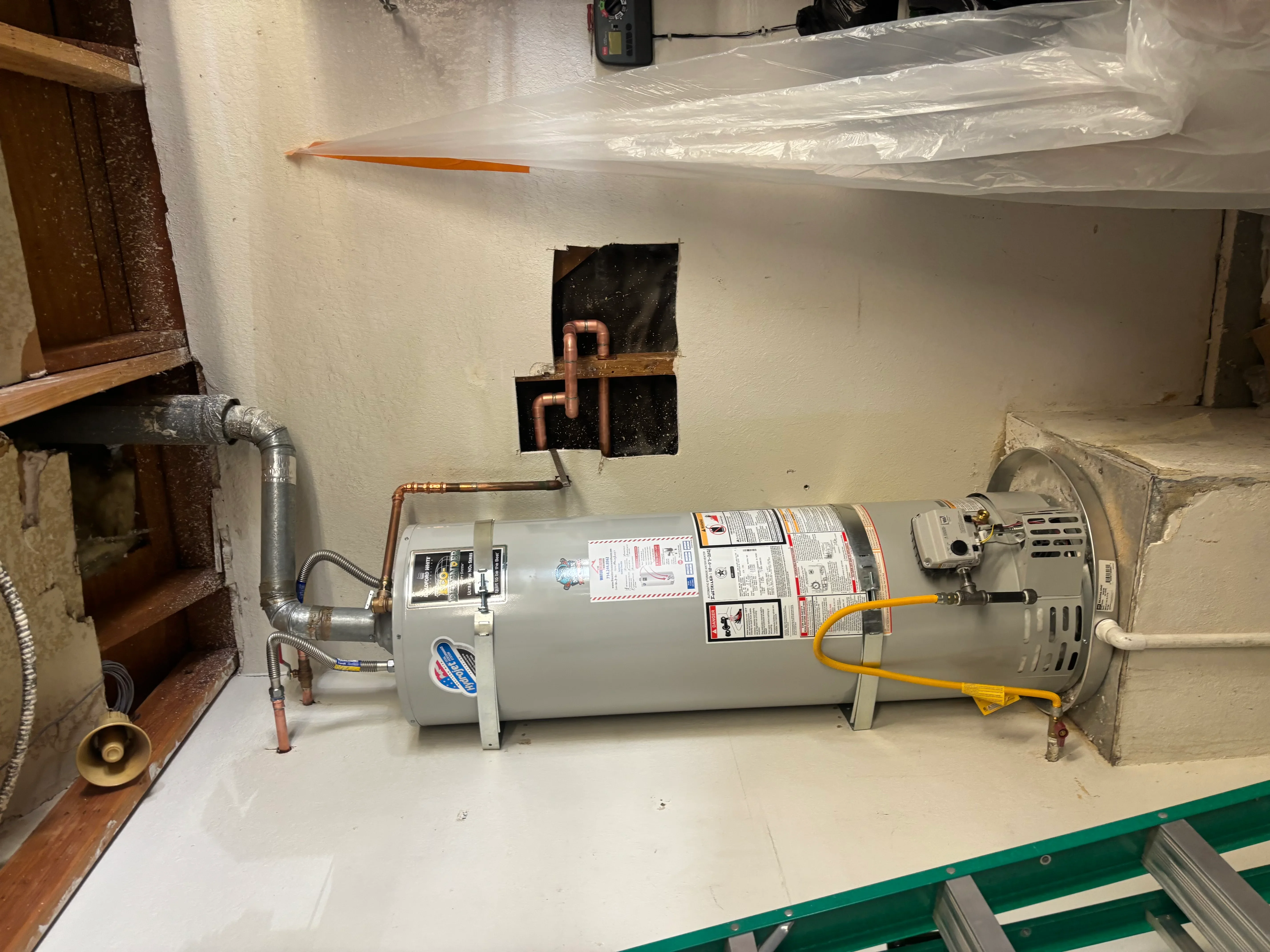 New water heater tank with copper piping connections and wall vent installation