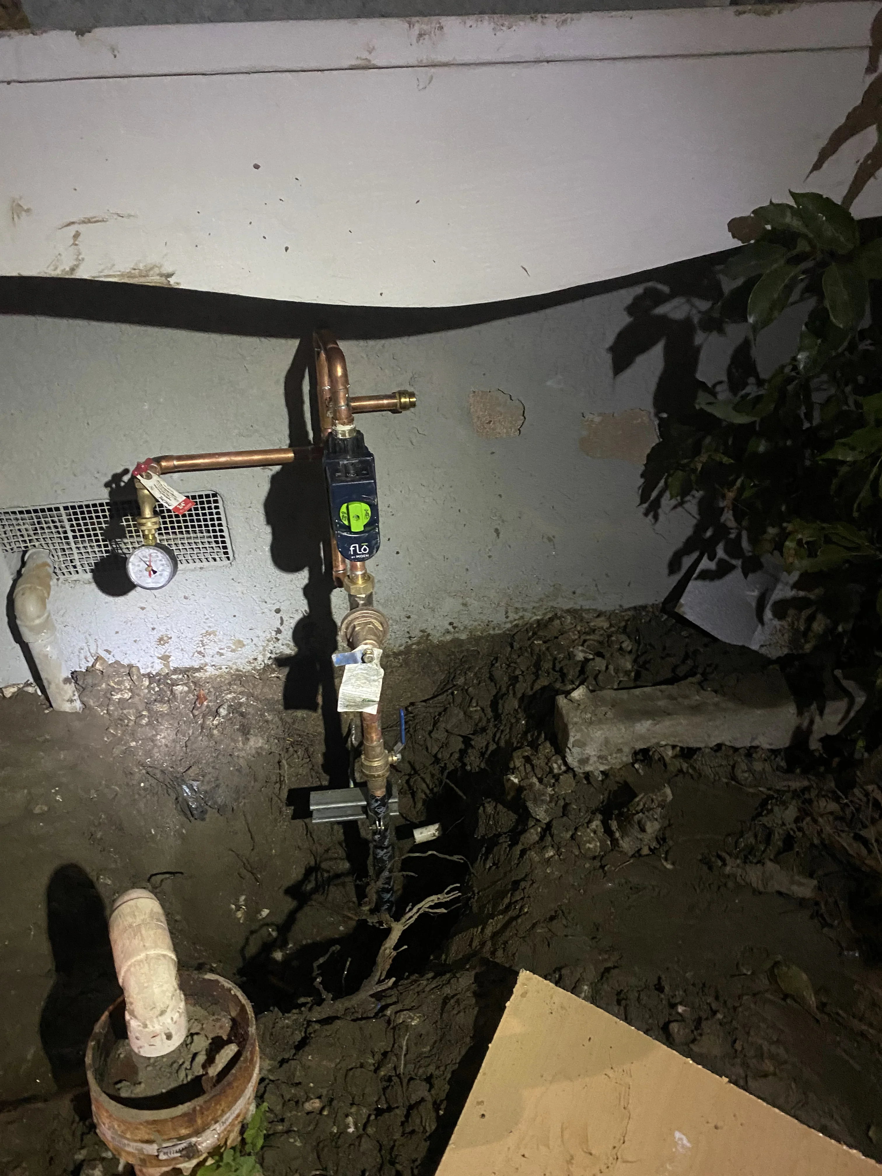 Copper and PEX plumbing lines with ball valves and pressure gauge in basement installation